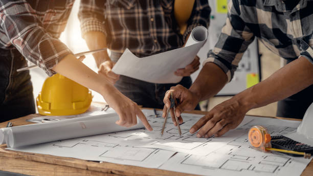 istock Two colleagues discussing data working and tablet, laptop with on on architectural project at construction site at desk in office. 1480028332
