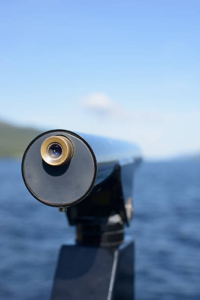 Telescope looking out over water and coastline on sunny day, focus on eye piece. Shot at Loch Ness, Scotland. Need clarity or to better see the future?