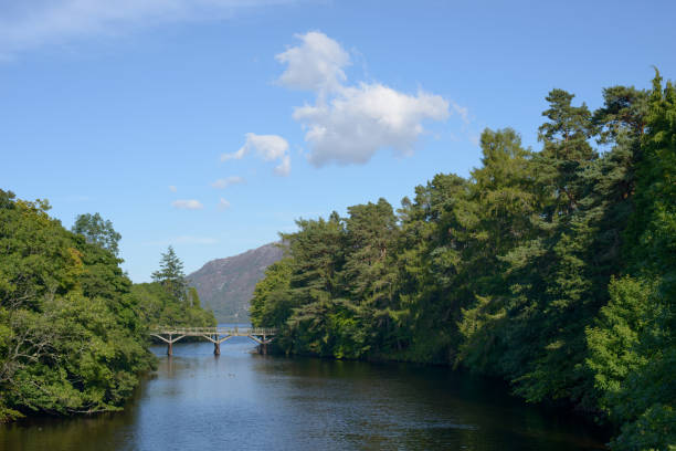 Scenic view of River Oich bridge at Fort Augustus, Loch Ness, Scotland, looking towards the loch. Sunny day with blue sky and white clouds.
