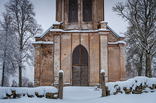 Entrance to old abandoned church of brick, broken doors. Selpils Evangelical Lutheran Church, Latvia. Winter landscape.