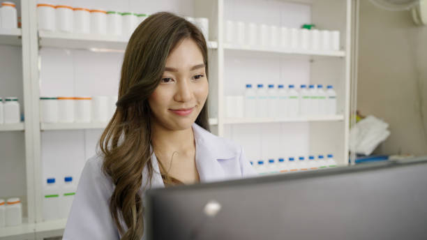 istock Smiling Asian pharmacist in drugstore or pharmacy using computer 1480032684