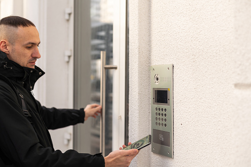 Cut in picture hand of a man turning on the intercom with smartphone outdoor close up