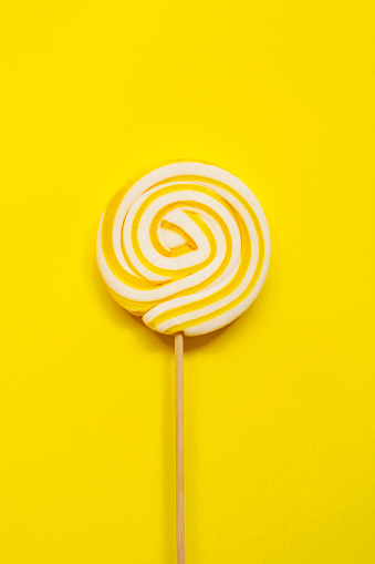 Yellow lollipop on yellow background