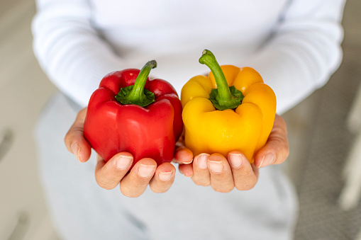 Hands hoding red and yellow peppers