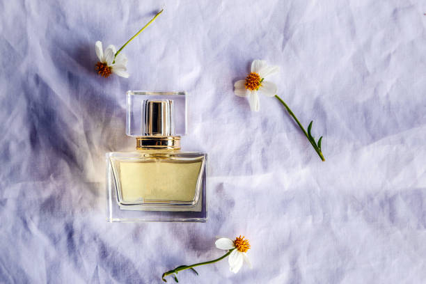 istock Golden perfume and small perfume bottles with a white flower on white cloth background,Top view 1480038652