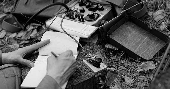 Infantry Army Soldier In World War II using Portable Radio Transceiver In Trench Entrenchment In Forest. . Headphones And Telegraph Key. Close Up Hands, Black And White Colors.