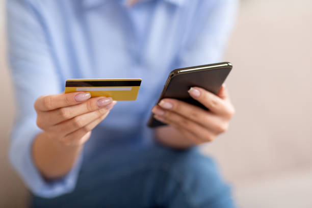 istock Unrecognizable lady holding cell phone and credit card 1480040259