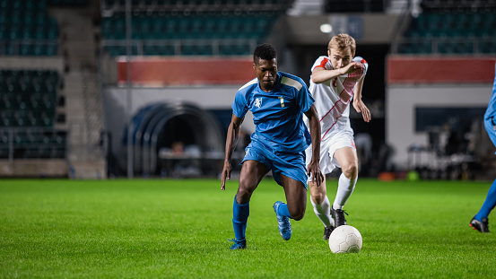 Soccer Football Match Event on a Major League Championship: Blue Team Attacks, Playing Pass, Dribbling. Action Game Tournament. Live Sport Channel Broadcast Television Concept.