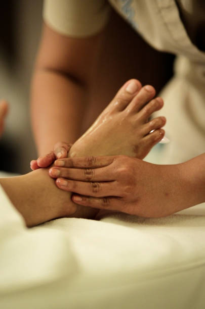 Thai Traditional Foot Massage,Physiotherapist giving foot massage to a woman,The hands of the massage therapist massage the foot in the process of a wellness massage of the whole body, Foot massage as a means to improve the overall health of the body masaje tradicional tailandés de pies, fisioterapeuta que da masaje de pies a una mujer, las manos del terapeuta de masaje masajean el pie en el proceso de un masaje de bienestar de todo el cuerpo, masaje de pies como un medio para mejorar la salud general