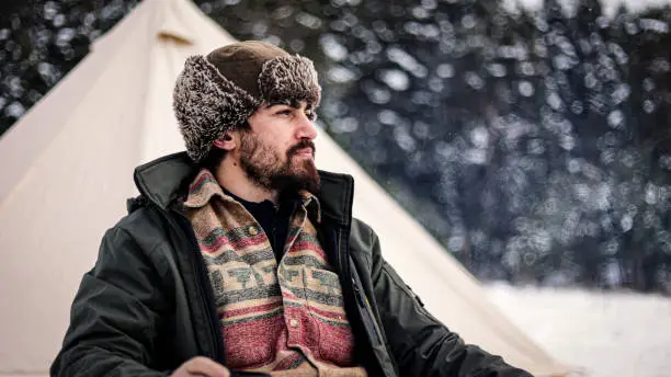 Camper in snowy winter mountain in ushanka hat drinking hot drink

A winter camper wearing a ushanka or hunting hat, winter mountain camper drinking hot coffee by the tent, cold camper drinking hot drink, human in nature away from everything, living free in nature
