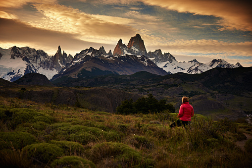 Woman in red jacket looking at  Mount Fitz Roy at dusk.