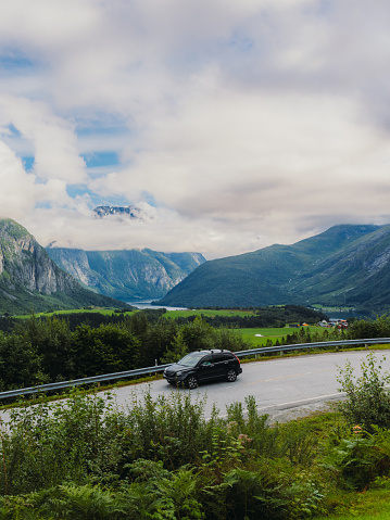 A car on the mountain pass through the fresh green fjord of Western Norway in Eidfjord, Scandinavia