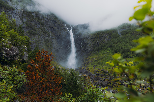 Low-angle view of the beautiful powerful waterfall hidden in the mountains during summertime in Scandinavia
