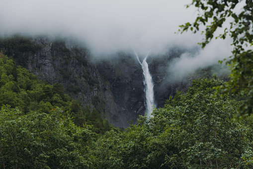 Low-angle view of the beautiful powerful waterfall hidden in the mountains during summertime in Scandinavia