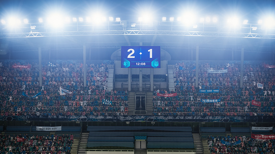 Football Soccer Stadium Championship Match, Scoreboard Screen Showing Score of 2:1. Crowd of Fans Cheering, Screaming, Having Fun. Sport Channel Television Advertising Concept