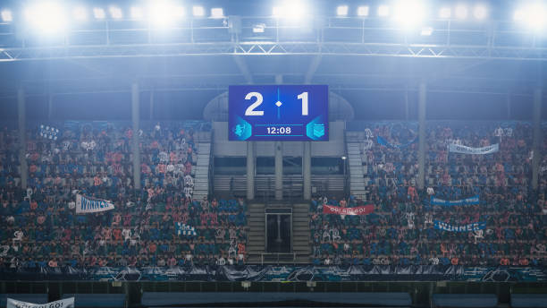 Football Soccer Stadium Championship Match, Scoreboard Screen Showing Score of 2:1. Crowd of Fans Cheering, Screaming, Having Fun. Sport Channel Television Advertising Concept. Wide Shot. partido del campeonato del estadio de fútbol de fútbol, pantalla de marcador que muestra una puntuación de 2: 1. multitud de fanáticos vitoreando, gritando, divirtiéndose. concepto de publicidad de televisión de canal deportivo. tiro amplio.