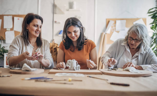 istock Women molding clay together 1480061255