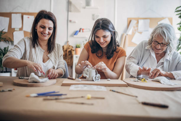 istock Women molding clay together 1480061340