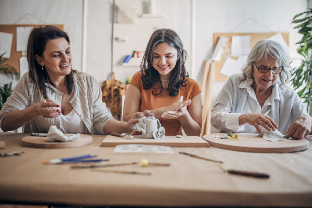 istock Women molding clay together 1480061366