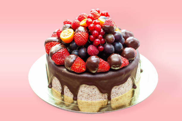 Cake decorated with strawberry dipped into melted chocolate, raspberry, blueberry and red currant. Isolated on plain background