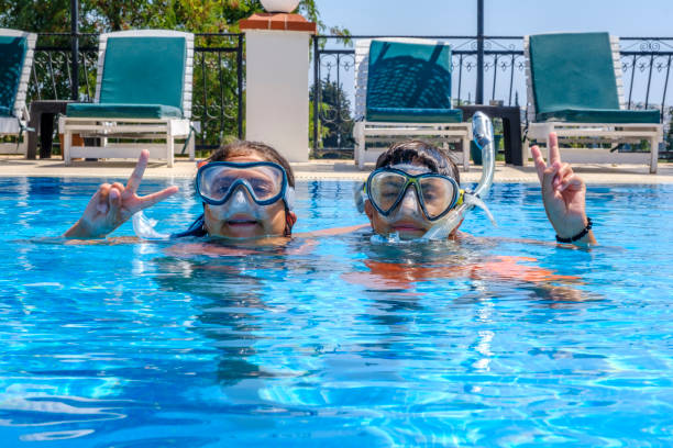 Boy and girl with snorkels posing in outdoor swimming pool Summer vacation concept: Family fun at outdoor hotel poolside. Brother and sister playing and enjoying. 10 years old girl and 12 years boy swimming in outdoor pool. vacation rental mask stock pictures, royalty-free photos & images