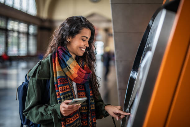 A beautiful young woman uses an ATM at a metro station in Barcelona, withdraws her money to go shopping stock photo