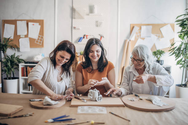 istock Women molding clay together 1480062431