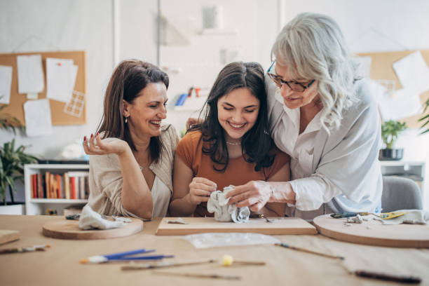 istock Women molding clay together 1480062466