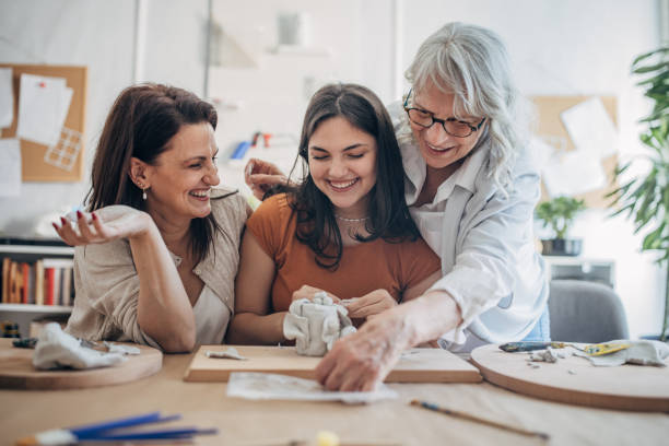istock Women molding clay together 1480062528