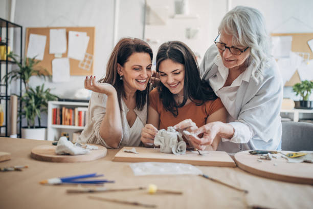 istock Women molding clay together 1480062635