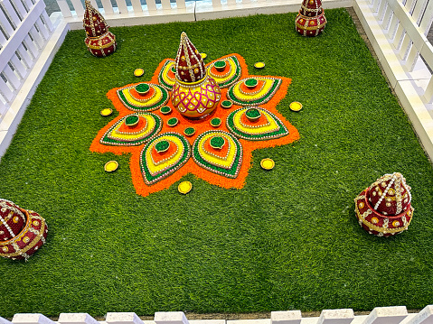 Stock photo showing an elevated view of a square of grass with Diwali rangoli design made from gulal (coloured powder paint) in celebration of Diwali the festival of lights.
