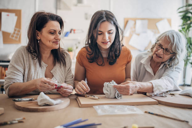 istock Women molding clay together 1480063784