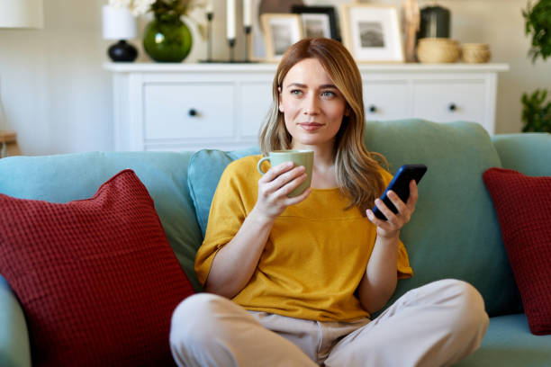 istock Woman using smartphone while drinking coffee at home in the morning 1480063841
