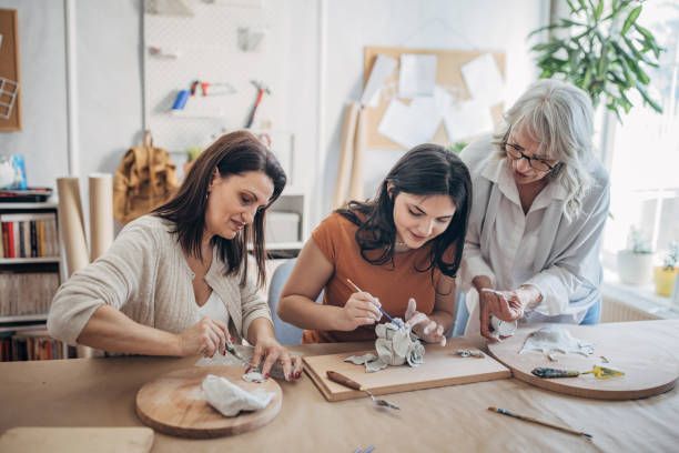 istock Women molding clay together 1480063886