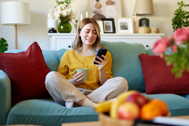 istock Woman using smartphone while drinking coffee at home in the morning 1480063907