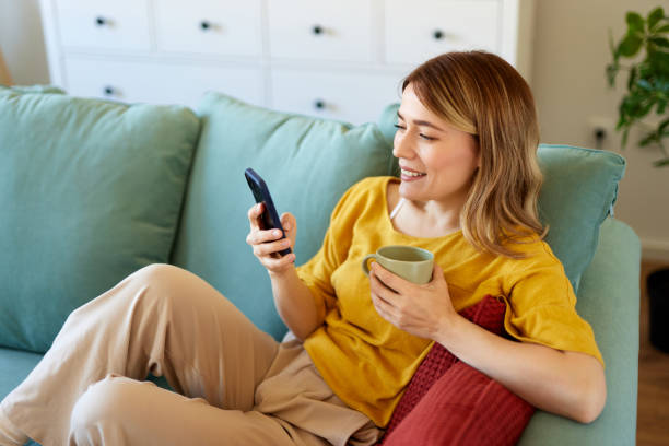 istock Woman using smartphone and drinking coffee at home in the morning 1480064320