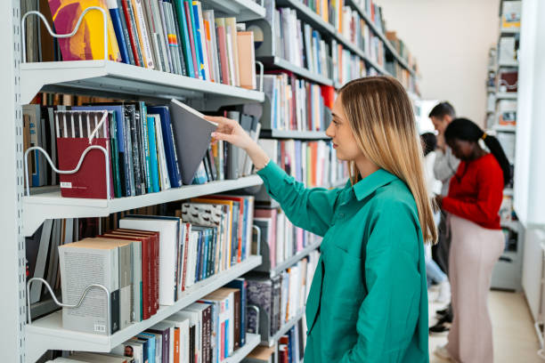 istock Female Student Picking Up A Book In A School Library 1480065476