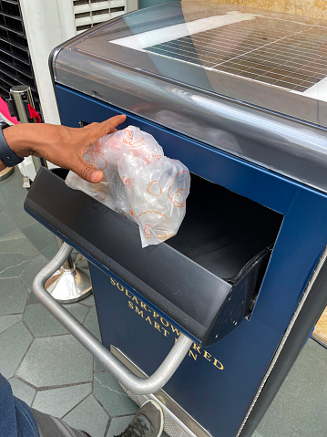 Stock photo showing close-up view of a modern smart trash can on the street. This solar-powered compactor enables a high capacity of rubbish to be collected in a smaller bin.