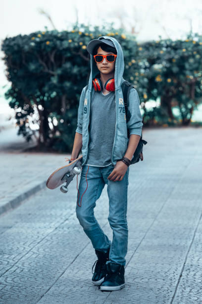 Portrait of a handsome active teen boy with skateboard in hands having fun outdoors. Youth passion. Sportive lifestyle of adolescent.