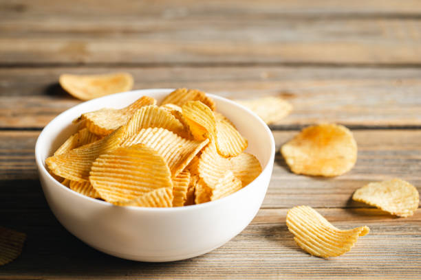 istock Potato chips in a bowl on a wooden background, close up. 1480071814