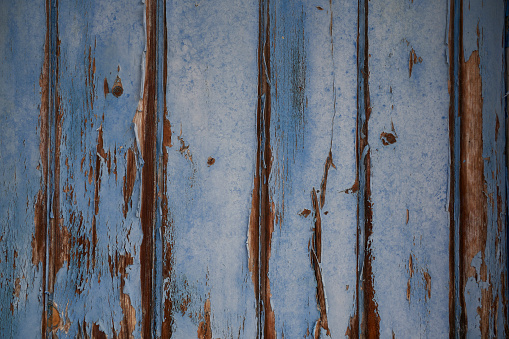 Peeling blue painted wooden old door background. Old weathered locker room fence from an abandoned swimming pool.