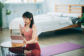 A female Asian is exercising at home, using a tablet for online training courses.