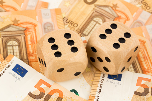 Two wooden dices on many euro money banknotes background.