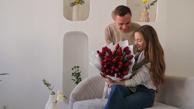 Guy gives a big bouquet to girl. She is surprised and kisses him back