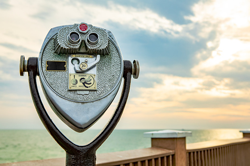 Blue tourist monocular with a beautiful mediterranean landscape in the background on a sunny summer day. Copy space for text.  Selective focus  \