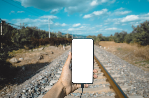 A man uses his mobile phone to shoot railway tracks outdoors