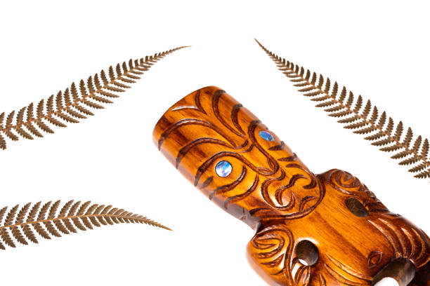 New zealand symbol, traditional maori carving and silver fern leaves, white background, close up New zealand symbol, traditional maori carving and silver fern leaves, white background, close up maori weaving stock pictures, royalty-free photos & images