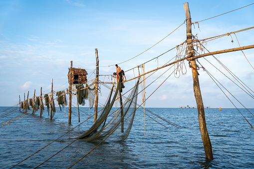 Tra Vinh province, Vietnam - 02 April 2023: fishermen pulling a nets on fishing poles at sea in Tra Vinh province, Vietnam, Asia during sunrise, local people call it is Day hang khoi.