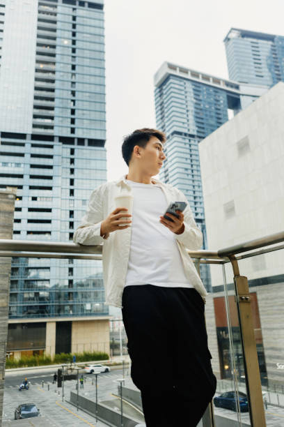 On a cloudy day in Shangcheng, Shenzhen City, Guangdong Province, a male businessman rested on a balcony outside the company, drinking coffee - drinking a cup of coffee after work to promote health and work life balance en un día nublado en shangcheng, ciudad de shenzhen, provincia de guangdong, un hombre de negocios descansó en un balcón fuera de la empresa, bebiendo café, bebiendo una taza de café después del trabajo para promover la salud y el equilibrio entre la