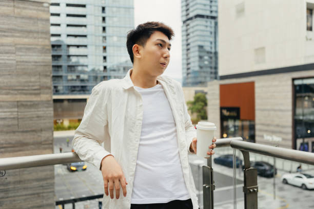 On a cloudy day, a male businessman is resting on a coffee break on the balcony outside the company - drinking a cup of coffee after work, promoting health, work life balance en un día nublado, un hombre de negocios está descansando en un descanso para tomar café en el balcón fuera de la empresa, bebiendo una taza de café después del trabajo, promoviendo la salud y el equilibrio entre la vida laboral y personal.